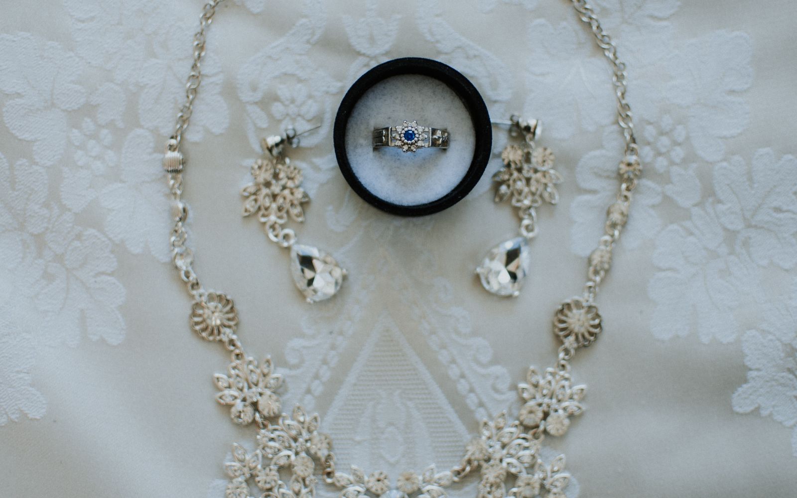 Classic necklace, earrings, and ring arranged on a light background