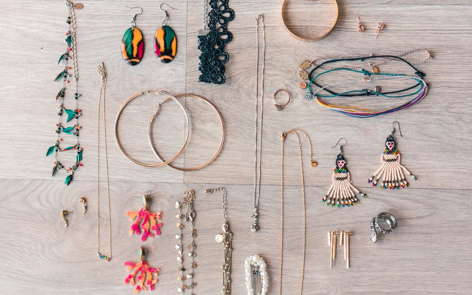 A varied collection of necklaces, rings, bracelets, and earrings on a wooden surface