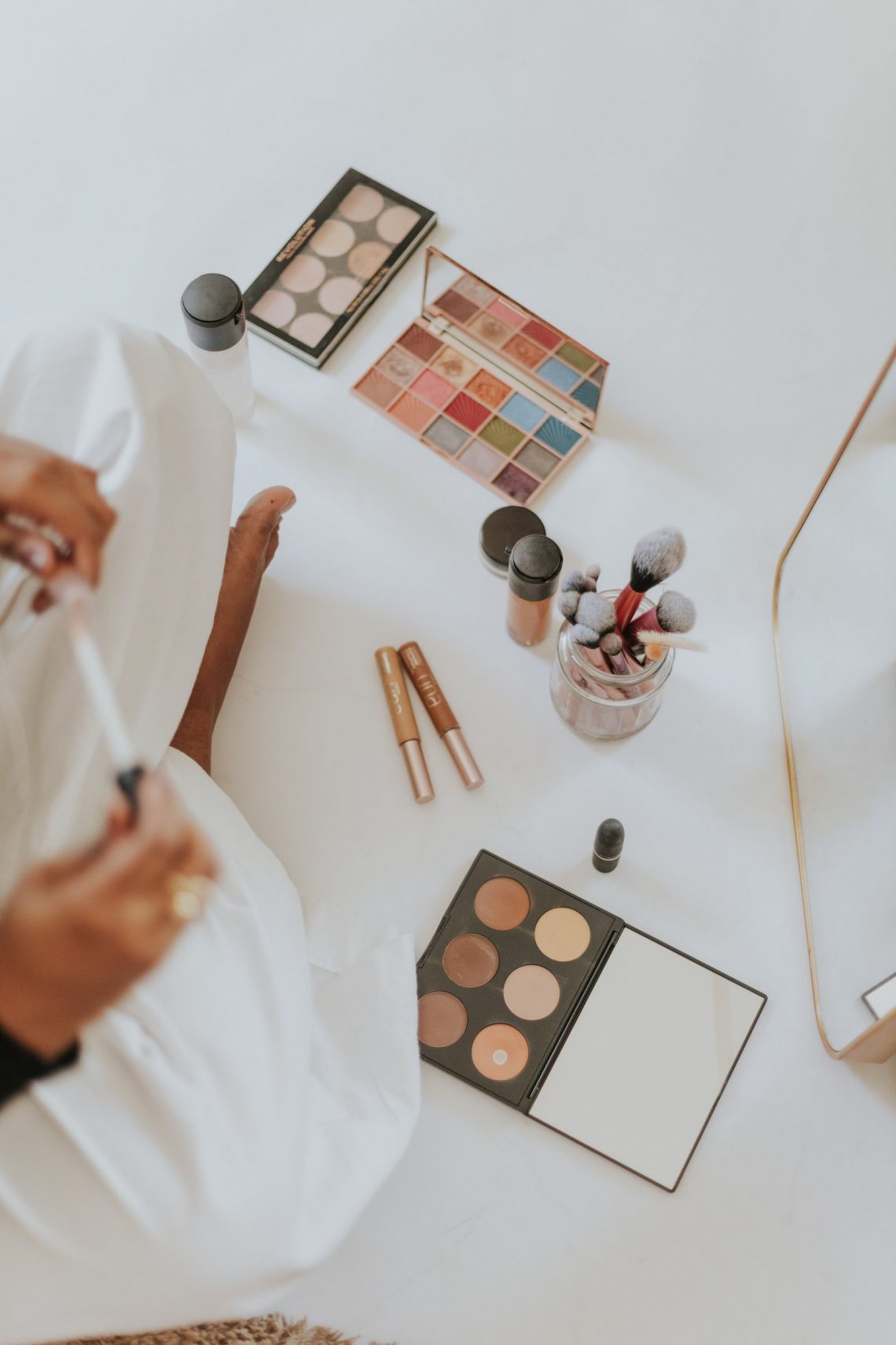Makeup products and brushes arranged on a light background