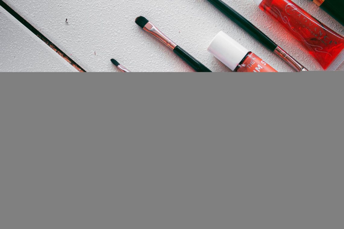 Makeup products and brushes arranged on a clean white surface