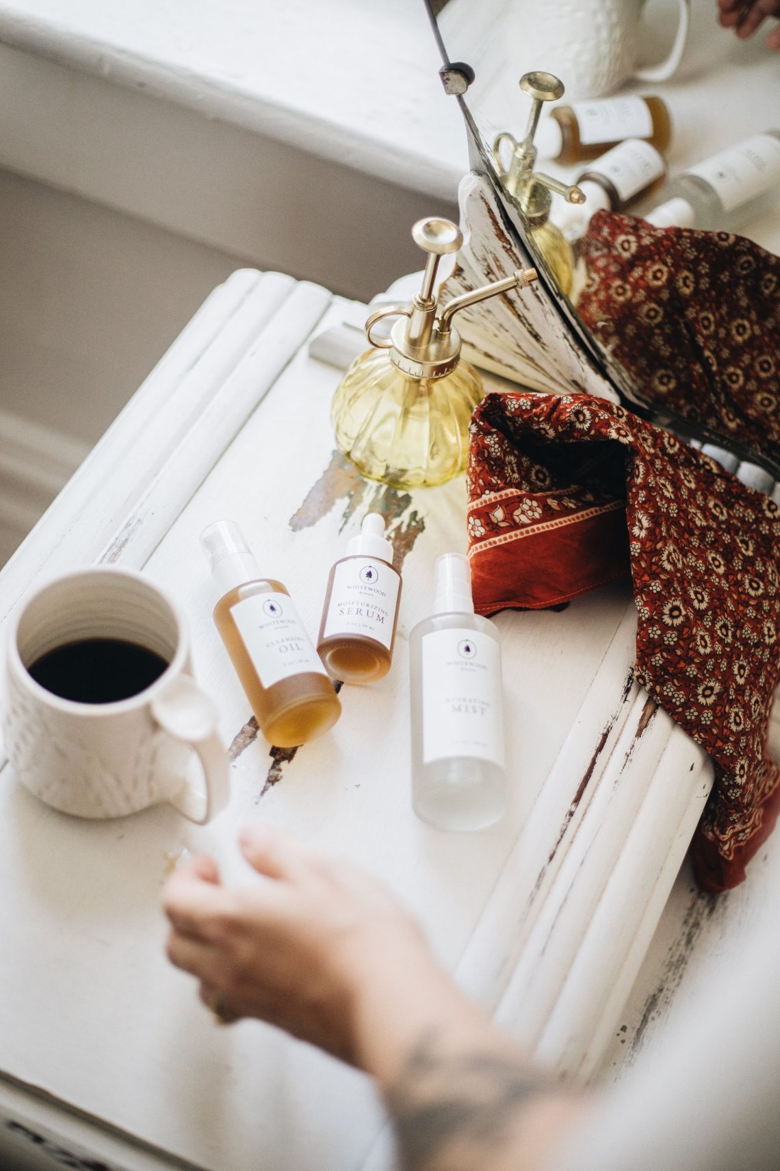 Skincare products with coffee and a cozy scarf in warm light