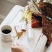 Skincare products with coffee and a cozy scarf in warm light